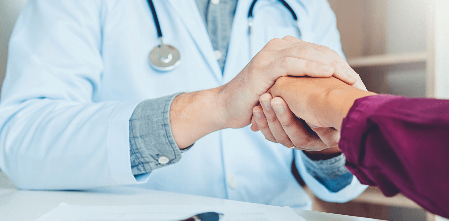 Doctor holding hand with patient.